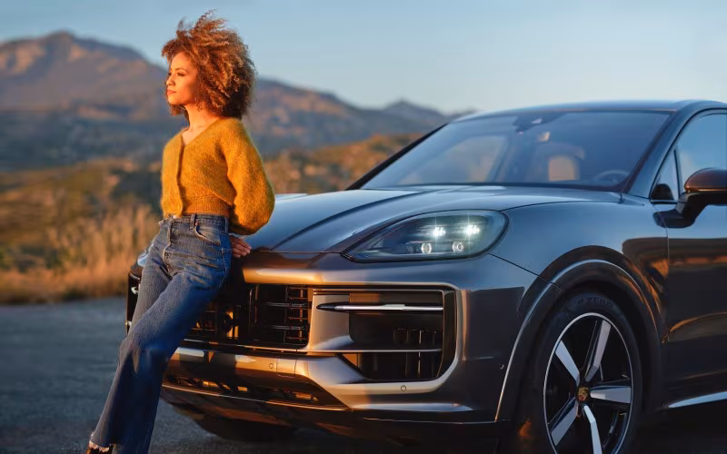 Woman leaning on a Porsche Cayenne.