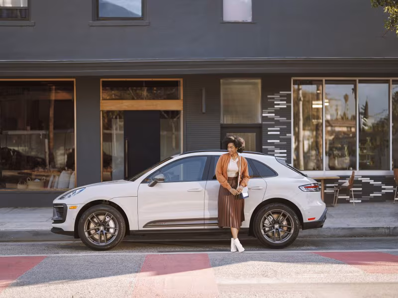 Woman standing in front of a Porsche Macan.